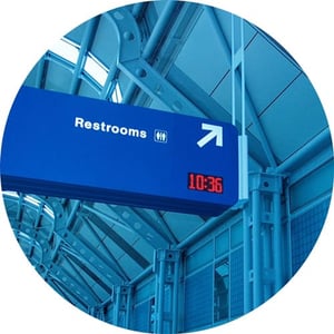 Blue sign pointing to restrooms inside airport.