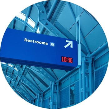 Blue sign pointing to restrooms inside airport.