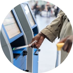 Woman grabbing ticket from self-check-in kiosk at airport.