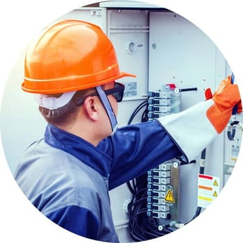 Facilities technician in a hard hat checks a breaker.