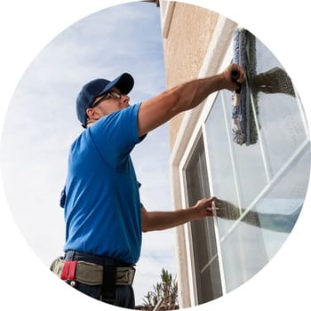 Maintenance man cleaning a window from the outside.